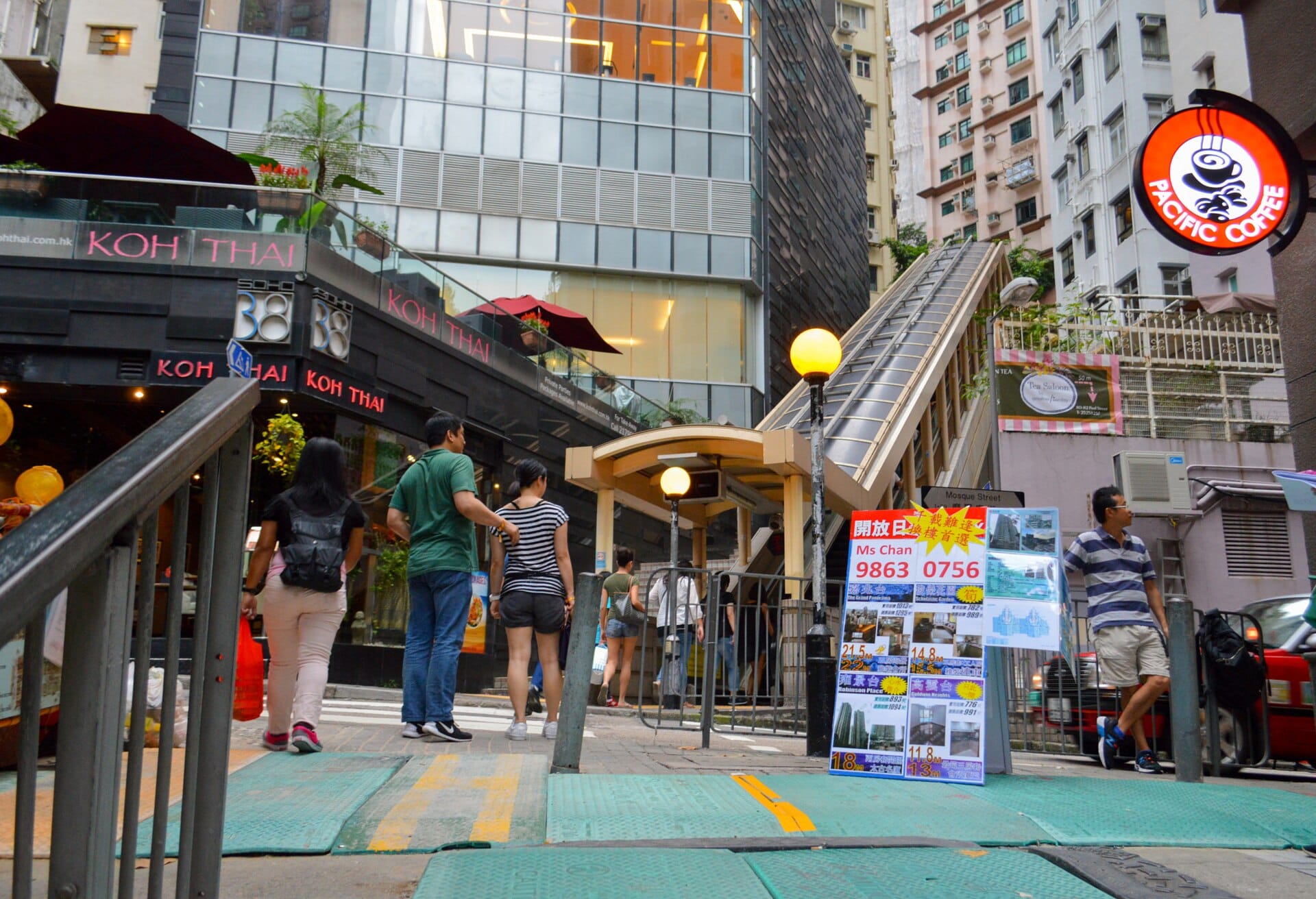 L'ingresso affollato della scala mobile del Mid-Levels a Hong Kong, con edifici urbani e la vista stradale di giorno.