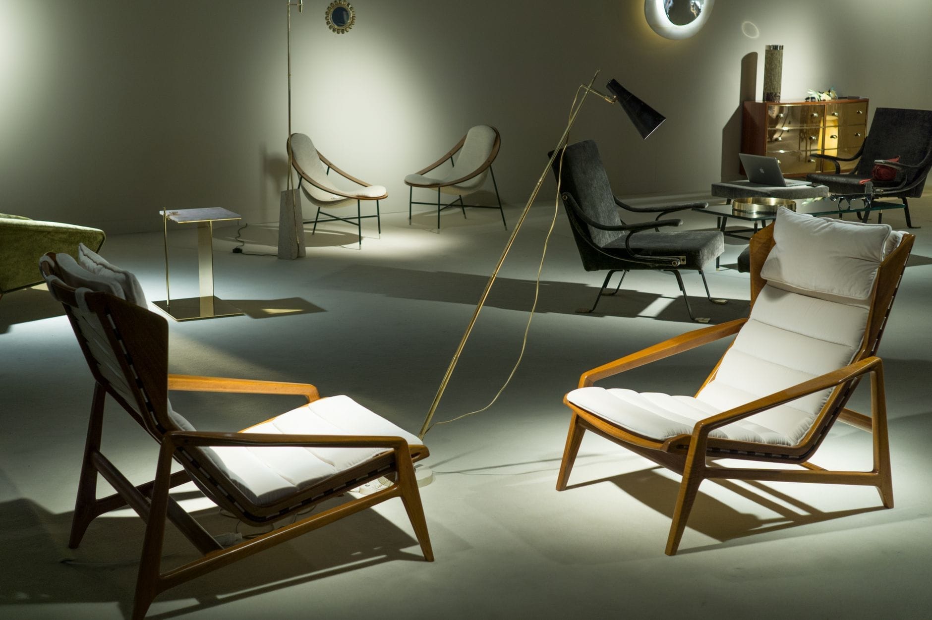 Poltronas modernas e móveis estilosos de meados do século são exibidos sob iluminação suave no espaço expositivo do Milan Design Week Salone del Mobile.