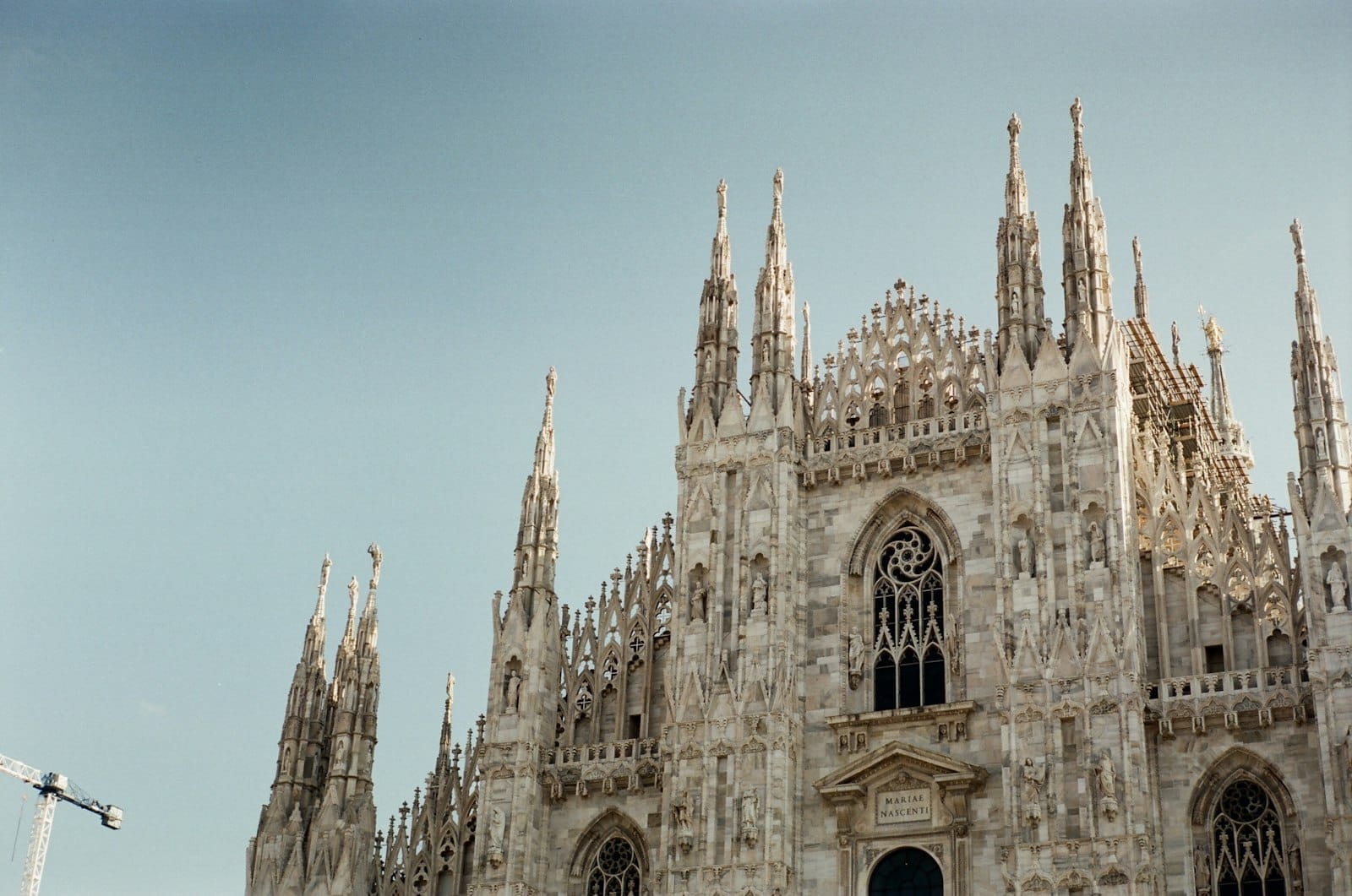 Detailed view of the Milan Cathedral (Duomo di Milano) spires shot against a clear blue sky, highlighting its iconic gothic architecture.