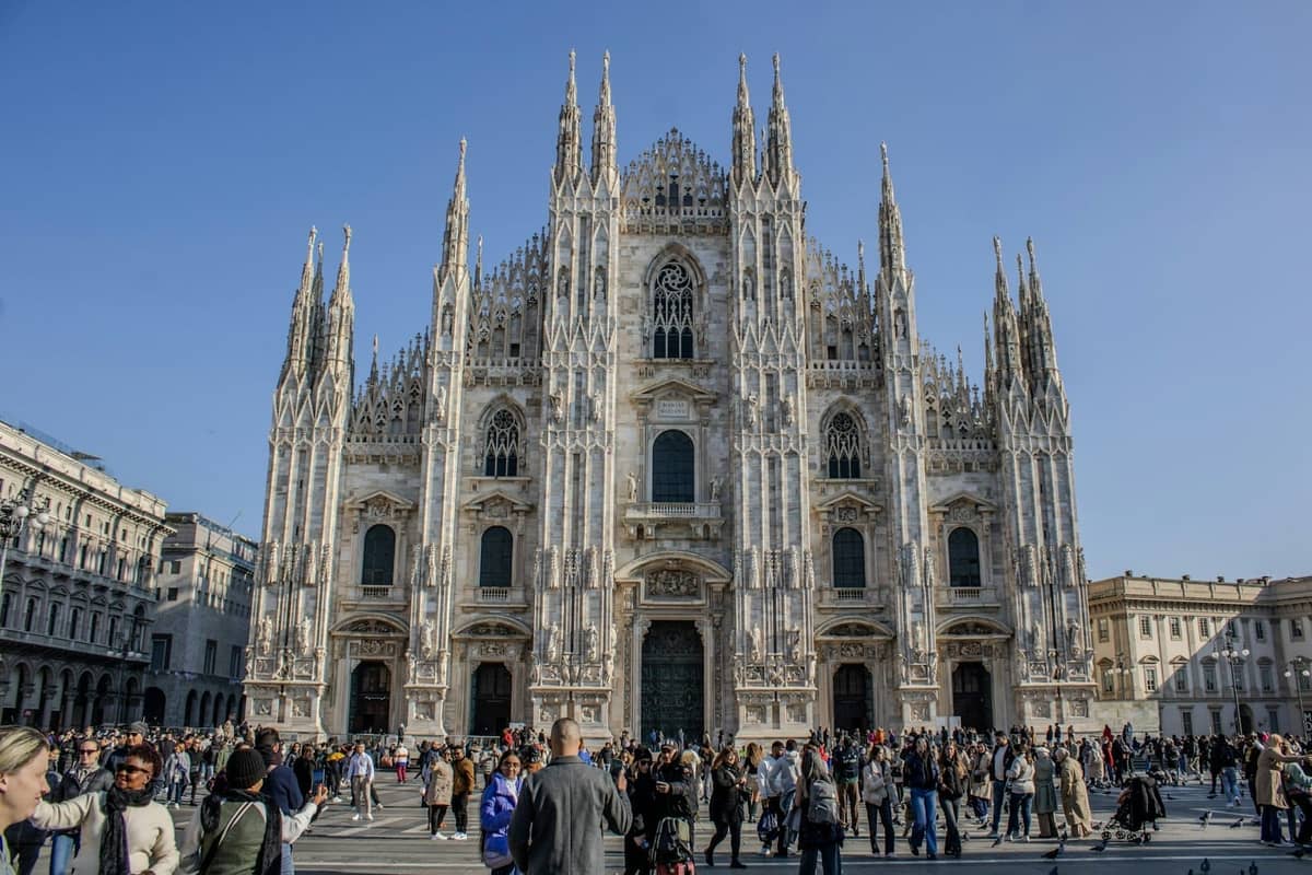 Überfüllte Piazza vor dem prunkvollen Duomo von Mailand unter klarem blauem Himmel, klassisches Wahrzeichen im Centro Storico.