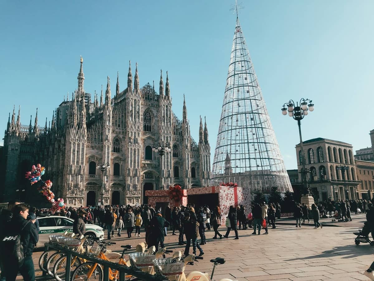 Menschenmenge vor dem Mailänder Dom und einer großen modernen Weihnachtsbaumstruktur in der Wintersonne