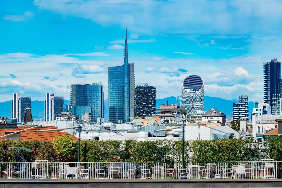 Dachterrasse mit Tischen und Stühlen mit Blick auf die Skyline von Mailands Porta Nuova und die Wolkenkratzer an einem hellen Tag.