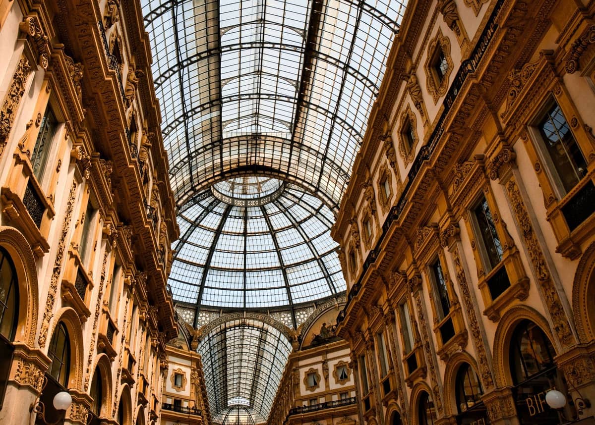 Widok wnętrza Galleria Vittorio Emanuele II w Mediolanie z ozdobnymi ścianami i ikonicznym szklanym sklepieniem beczkowym.