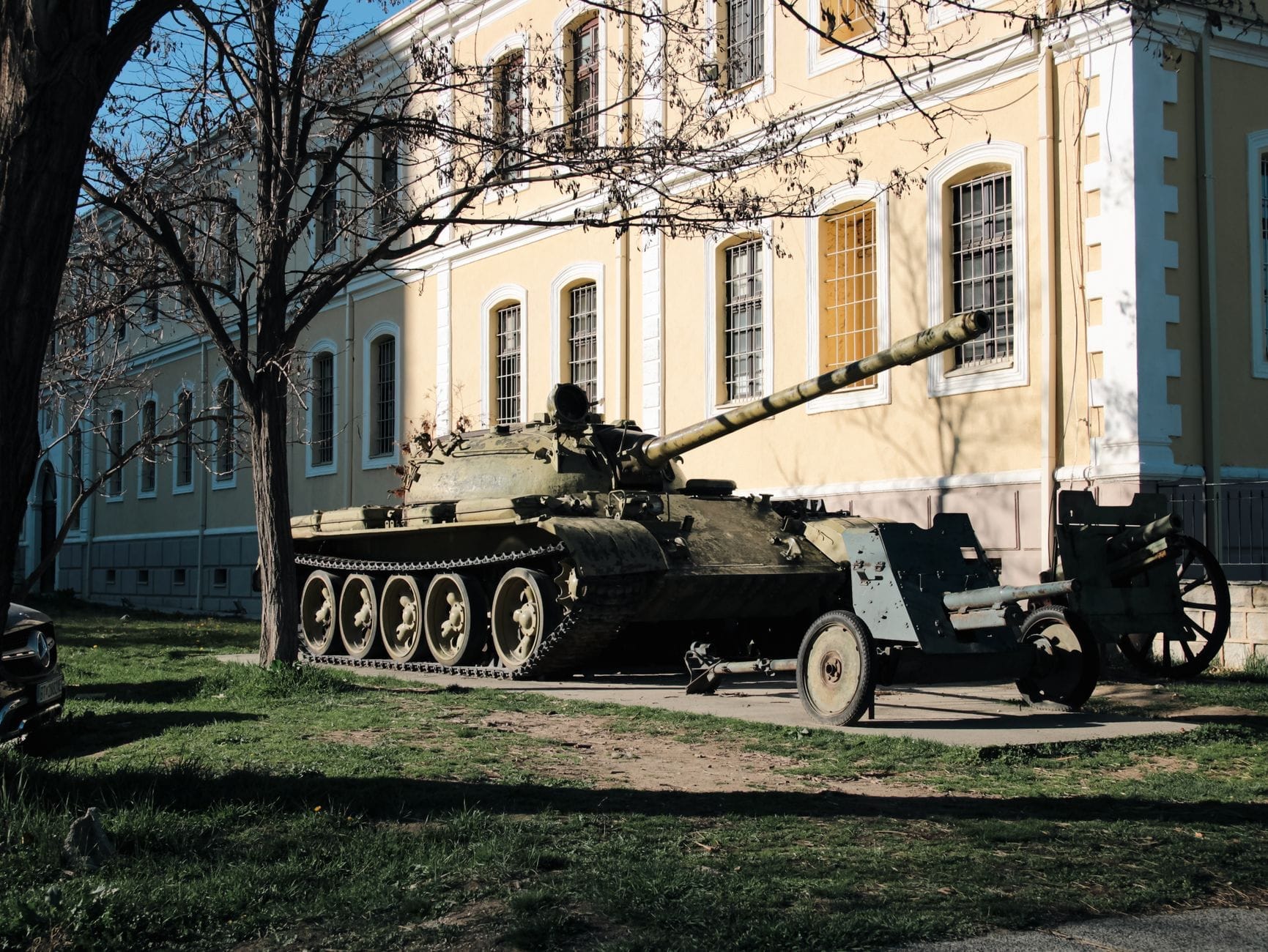 Un carro armato esposto all'aperto accanto all'edificio del Museo Militare di Istanbul, con la caratteristica architettura storica color ocra e le attrezzature militari sotto una luce diurna tersa.