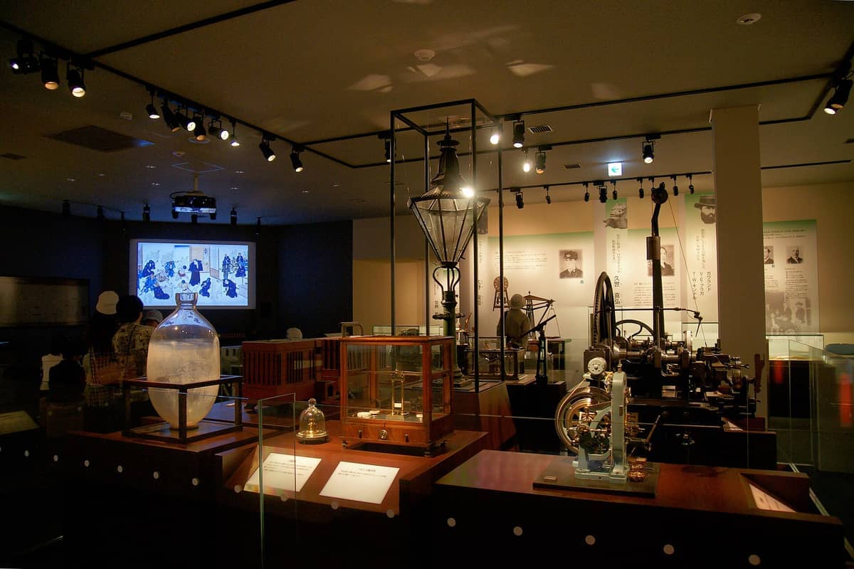 Exhibit room inside the Mint Museum Osaka, displaying vintage minting machinery, historical artifacts, and educational displays under warm ceiling lights.