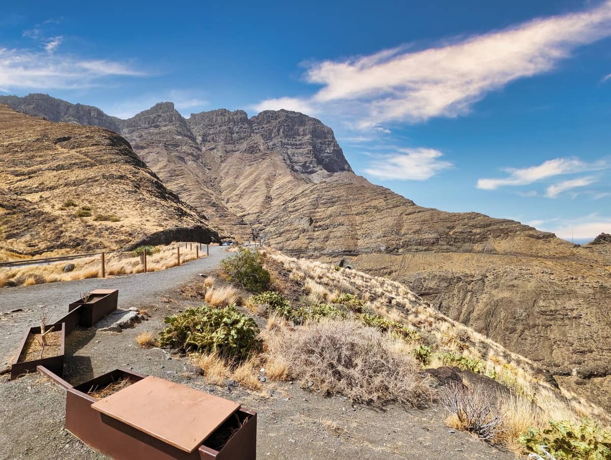Смотровая площадка Mirador del Balcón на Гран-Канарии: драматические вулканические скалы, Атлантический океан и каменистая тропа со скамейками над побережьем.