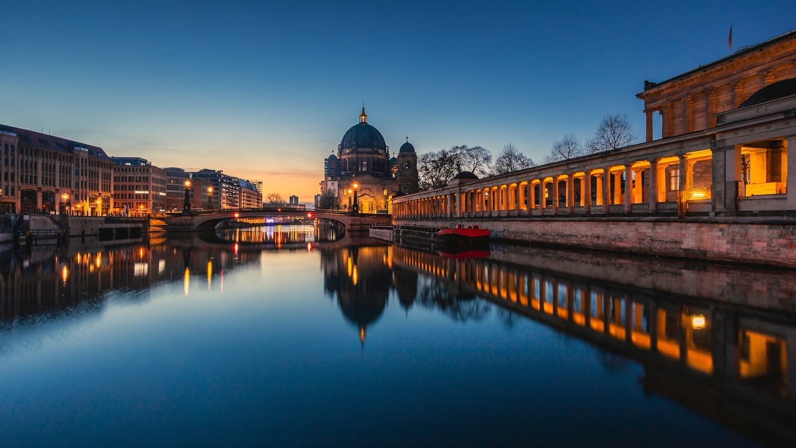 วิวพระอาทิตย์ตกสะท้อนแม่น้ำสเปร มองเห็นโบสถ์เบอร์ลินและ Museum Island ตึกเปิดไฟและท้องฟ้าโปร่งใจกลางเมือง