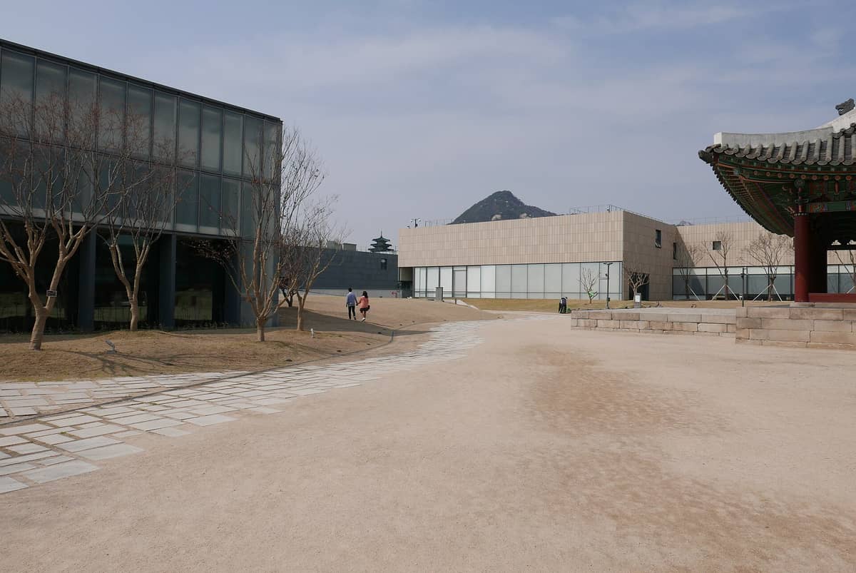Vista da filial de Seul do Museu Nacional de Arte Moderna e Contemporânea, com prédios modernos, árvores sem folhas e uma estrutura tradicional do palácio dentro do mesmo complexo.