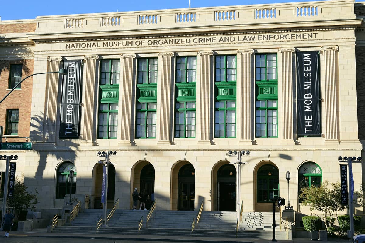 Bagian luar The Mob Museum di Las Vegas, menampilkan gedung pengadilan bersejarah dengan jendela hijau dan spanduk bertuliskan 'The Mob Museum'.