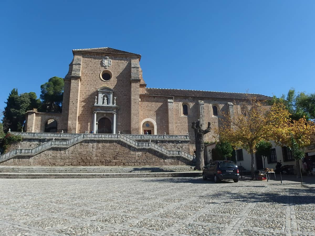 มุมมองด้านหน้าของ Monasterio de la Cartuja ในกรานาดา บันไดหิน ทางเข้าโค้ง และรายละเอียดบาโรกแบบเรียบง่าย ใต้ท้องฟ้าสีฟ้าใส