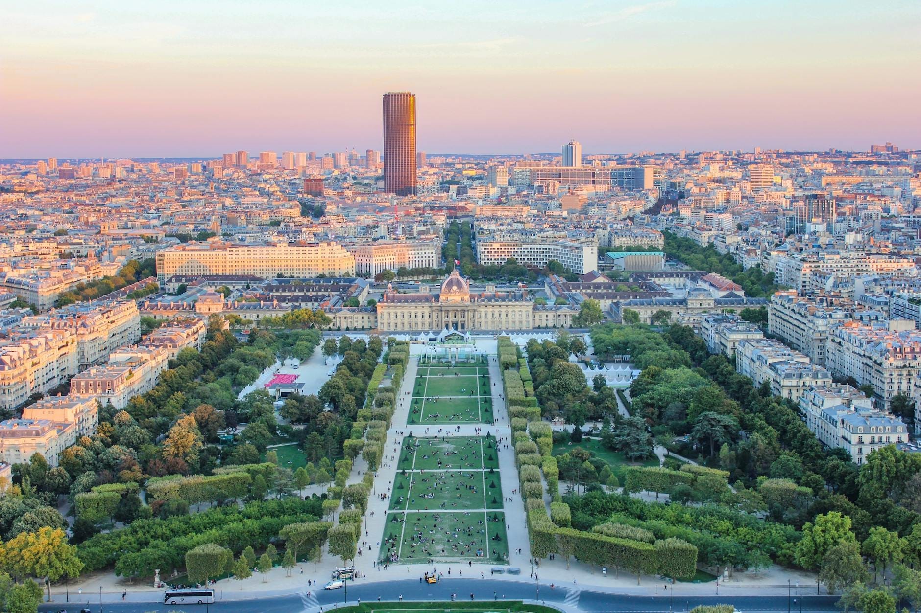 Vista panoramica di Parigi con la Tour Montparnasse al centro dello sfondo e il Champ de Mars che si estende verso il basso al tramonto.