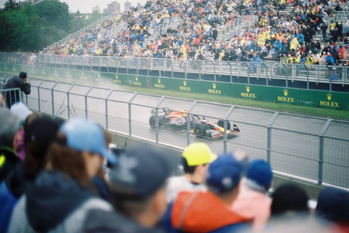 Formel-1-Autos rasen im Regen über den Circuit Gilles-Villeneuve in Montreal, während die vollbesetzten Tribünen den Kanadischen Grand Prix verfolgen.