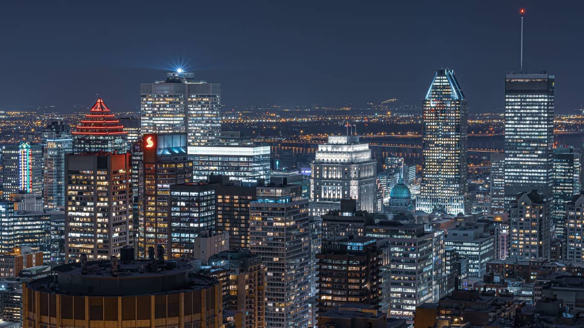 Nächtlicher Blick auf die Innenstadt von Montreal mit beleuchteten Hotels und Bürotürmen, der die lebhafte Stadtskyline und ideale Unterkunftsmöglichkeiten für Besucher zeigt.