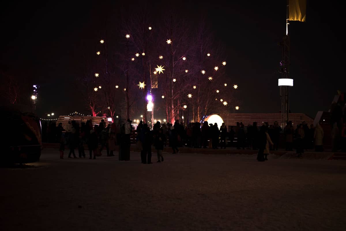ฝูงชนกลางแจ้งยามค่ำคืนพร้อมไฟประดับรูปดาวที่สว่างไสวในเมือง Montreal ที่ปกคลุมด้วยหิมะ สะท้อนบรรยากาศของเทศกาลฤดูหนาวหรืองานสาธารณะ
