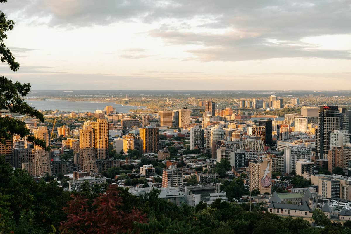 วิวภูมิทัศน์กว้างของย่านใจกลางเมืองและละแวกบ้านของ Montreal จากมุมสูง พร้อมอาคาร ต้นไม้สีเขียว และแม่น้ำในพื้นหลัง