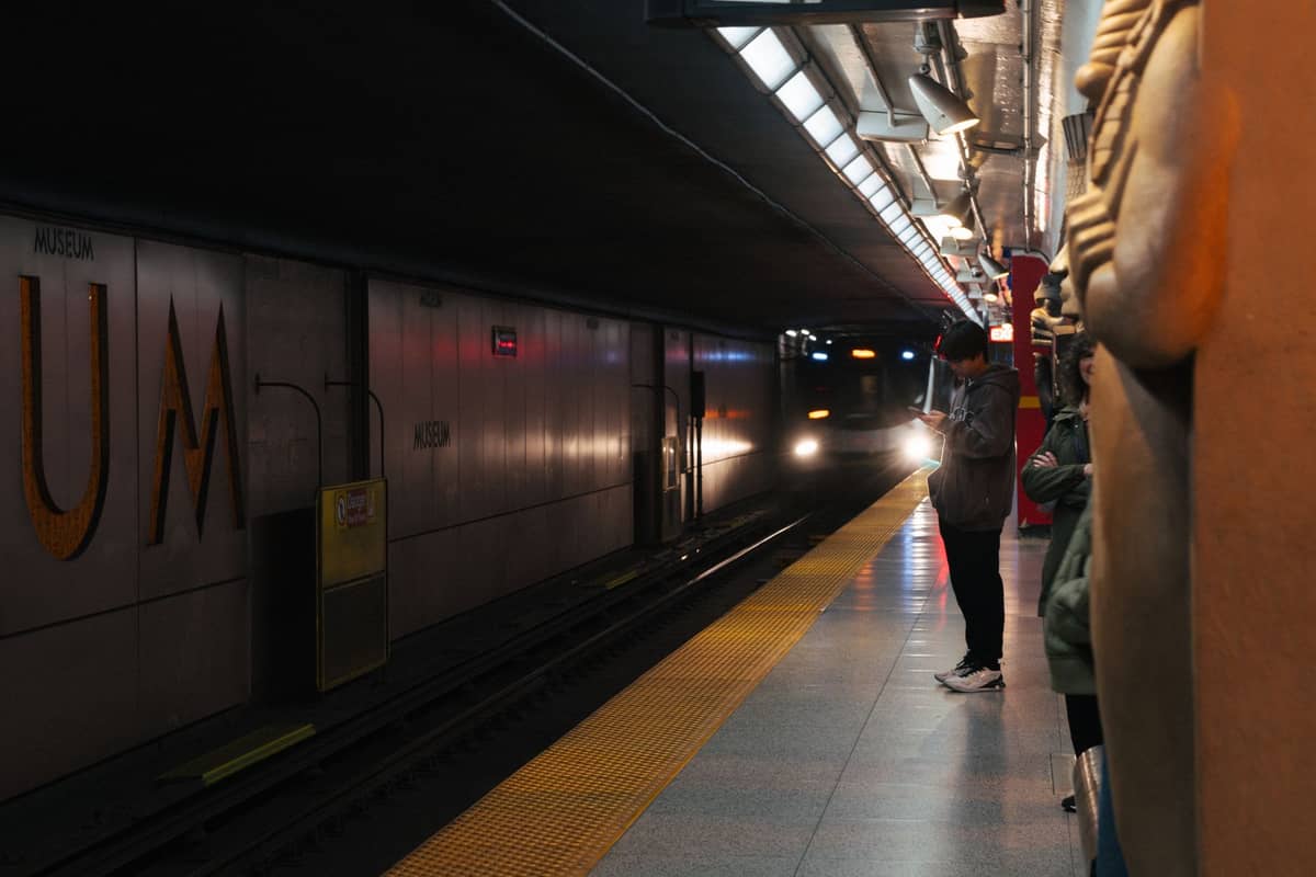 Personas esperando en el andén de una estación del metro STM de Montreal de noche mientras se acerca un tren.