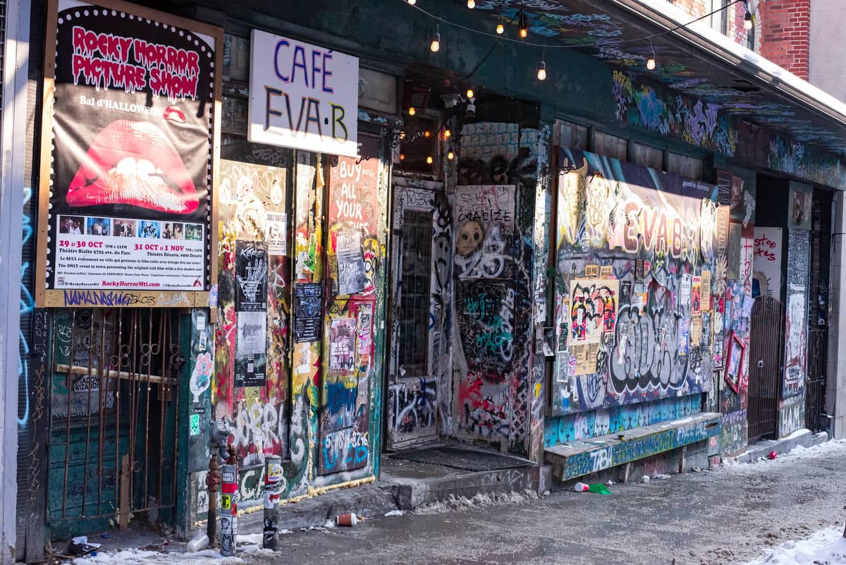 Zewnętrzna część Café Eva B na Boulevard Saint-Laurent pokryta graffiti, plakatami i sztuką uliczną zimą.