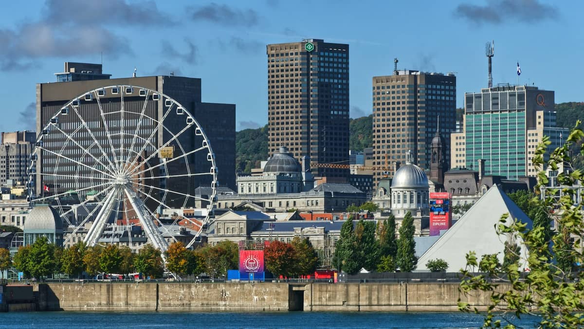 Panoramablick auf Montreals Alten Hafen mit dem Riesenrad La Grande Roue, der Kuppel des Bonsecours-Markts und der Innenstadt-Skyline an einem sonnigen Tag.