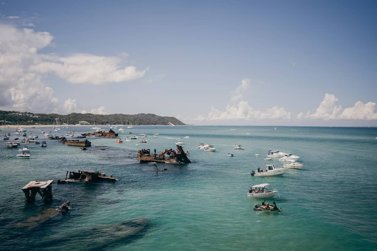 มุมมองซากเรือจม Tangalooma Wrecks อันโด่งดังที่เกาะมอร์ตัน เรือจอดในน้ำใสสีฟ้าสดใสกับท้องฟ้าเปิด