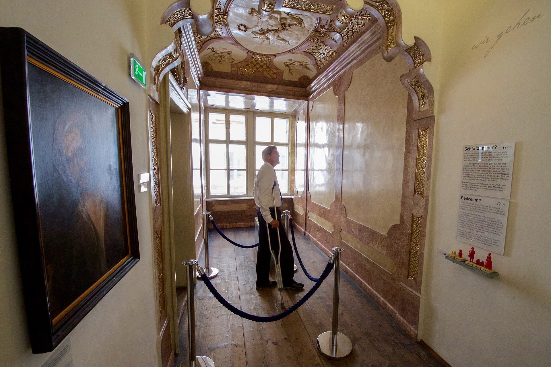US-Außenminister Kerry steht in einem sonnendurchfluteten, reich verzierten Flur im Mozarthaus Vienna, mit historischen Holzböden, bemalter Decke und informativen Tafeln an der Wand.