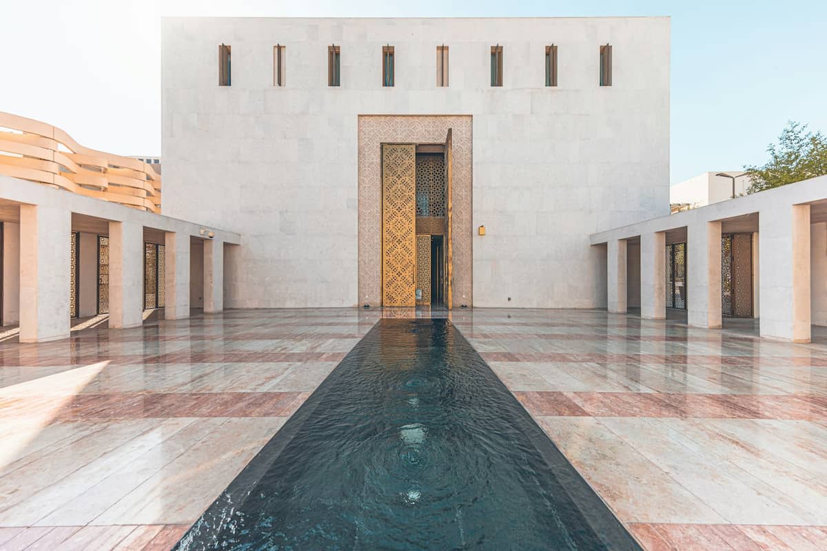 Ein restauriertes Kulturhaus im Msheireb-Museumskomplex mit einem modernen Innenhof, einem zentralen Wasserelement und minimalistischer geometrischer Architektur.
