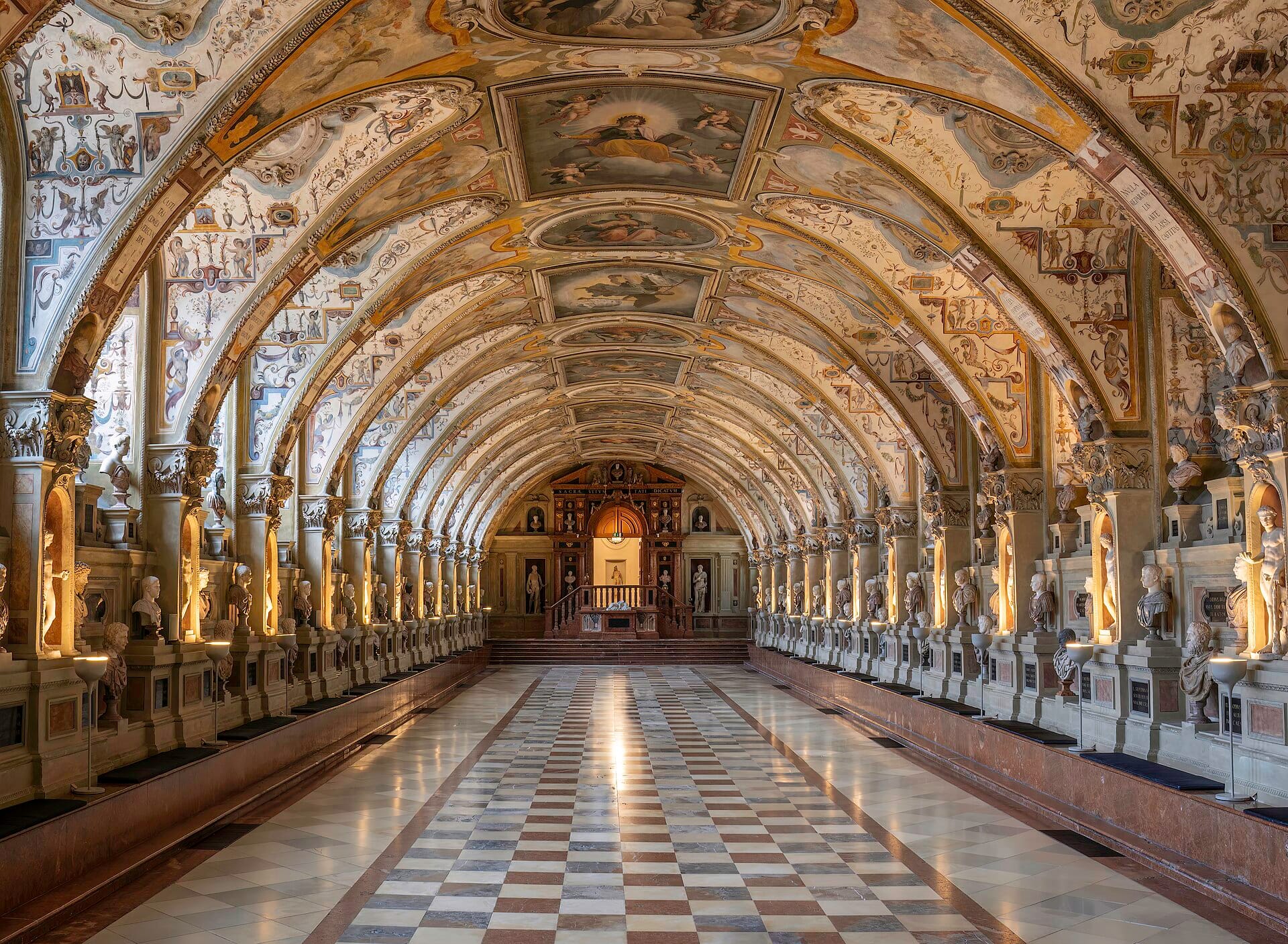 ภาพกว้างของห้อง Antiquarium ใน Munich Residenz หลังคาทรงโค้งตกแต่งวิจิตร รูปปั้นศีรษะเรียงราย และพื้นหินอ่อนลายตารางหมากรุก