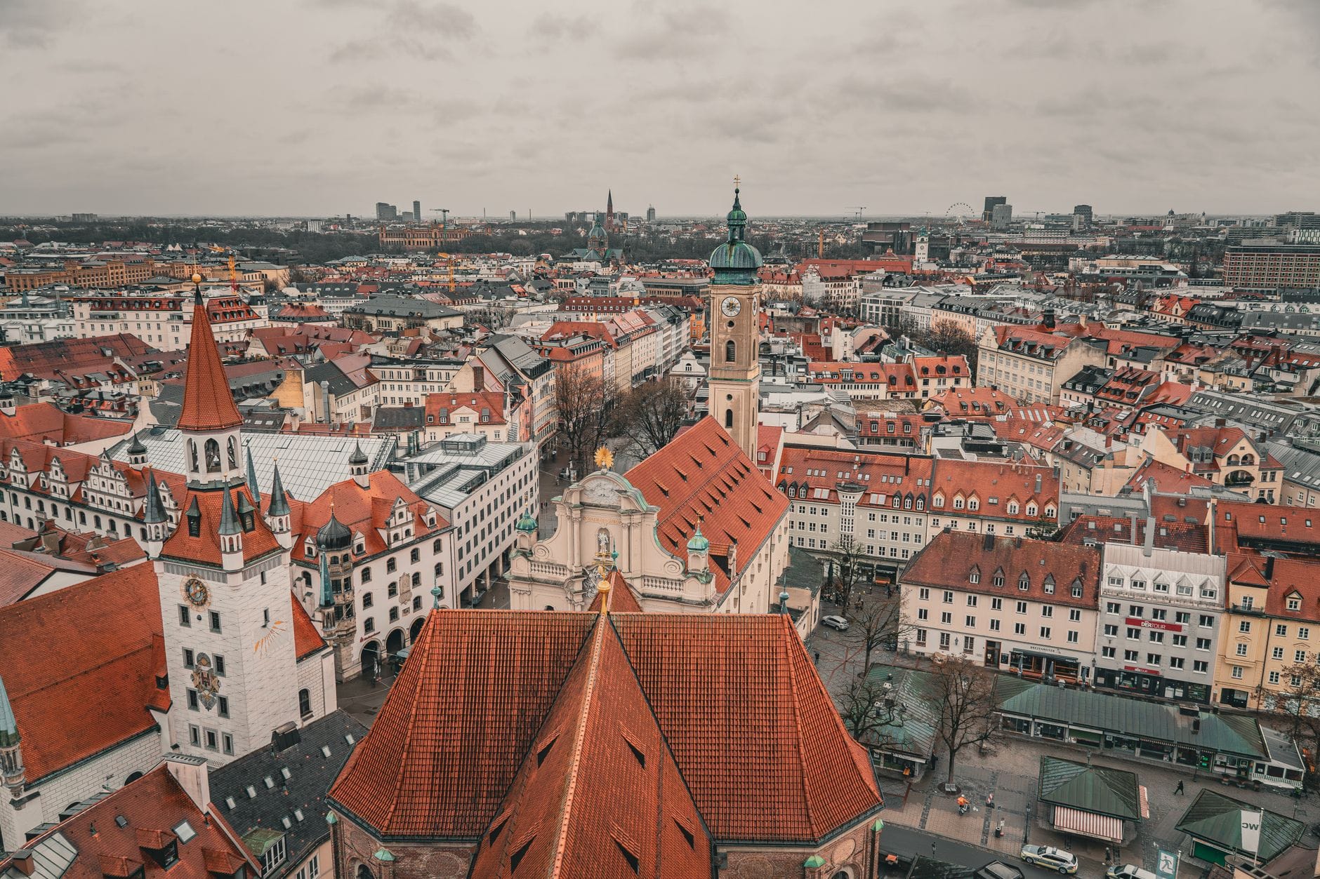 มุมมองทางอากาศของใจกลางเมือง Munich โดยมีหอคอยของโบสถ์ St. Peter โดดเด่นท่ามกลางอาคารหลังคาสีแดงในวันที่มีเมฆมาก