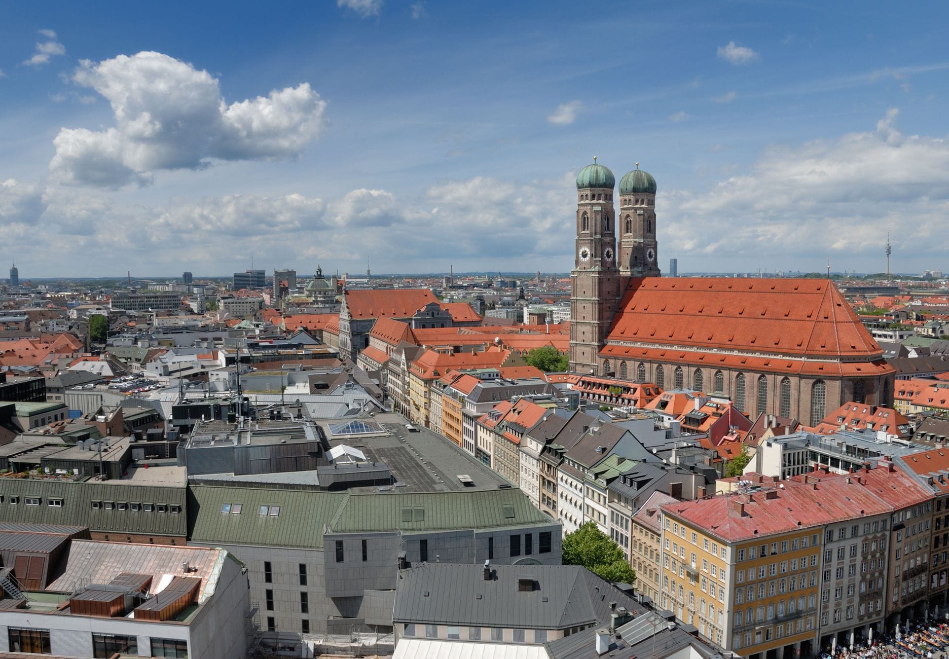 วิวกว้างจากดาดฟ้าเหนือใจกลางเมืองมิวนิกพร้อมมหาวิหาร Frauenkirche อันโด่งดังและอาคารโดยรอบภายใต้ท้องฟ้าสดใส
