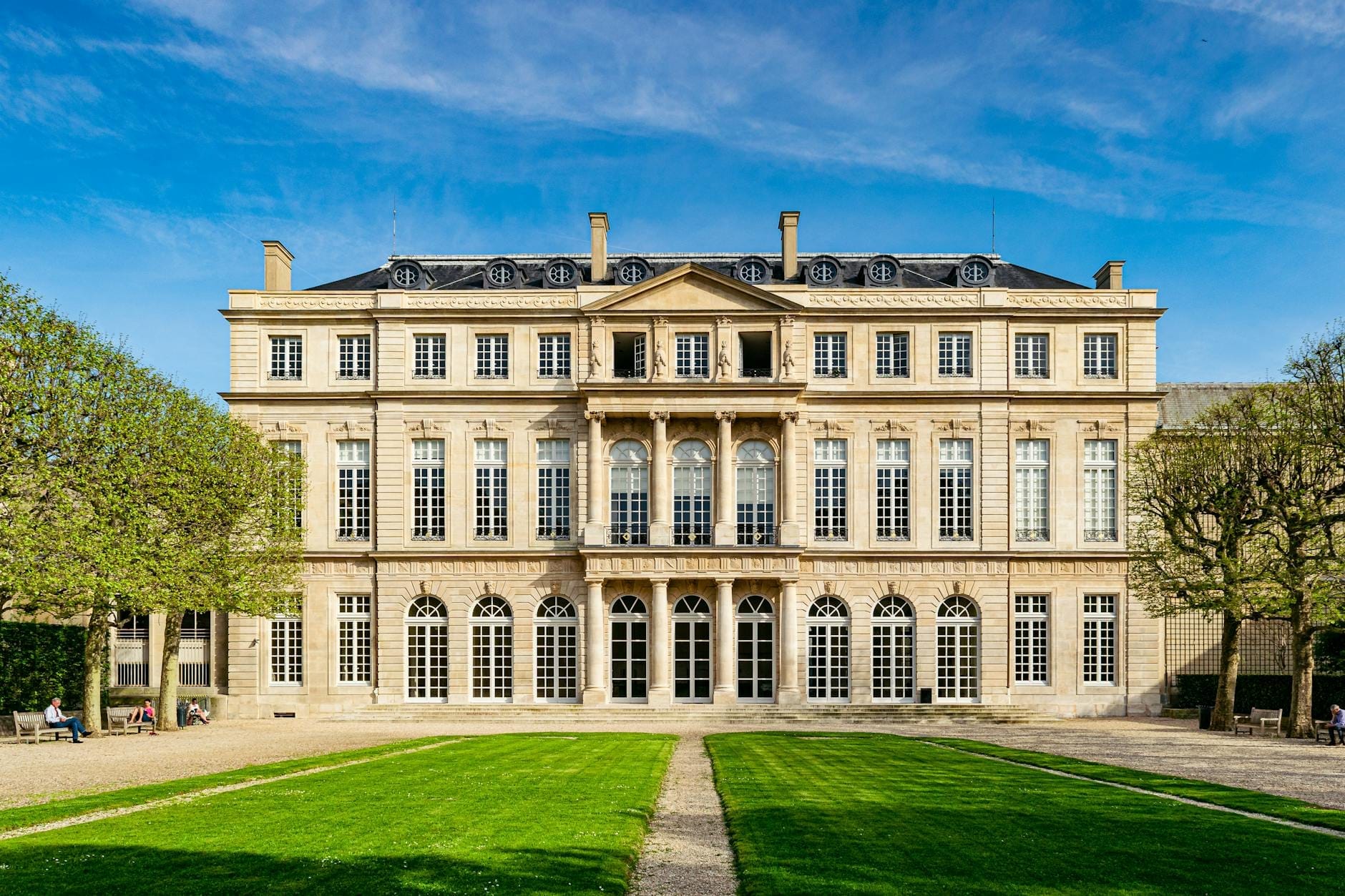 La raffinata facciata cinquecentesca del Musée Carnavalet con le finestre ad arco, il prato curato e il cielo azzurro, che invita a scoprire la storia di Parigi.