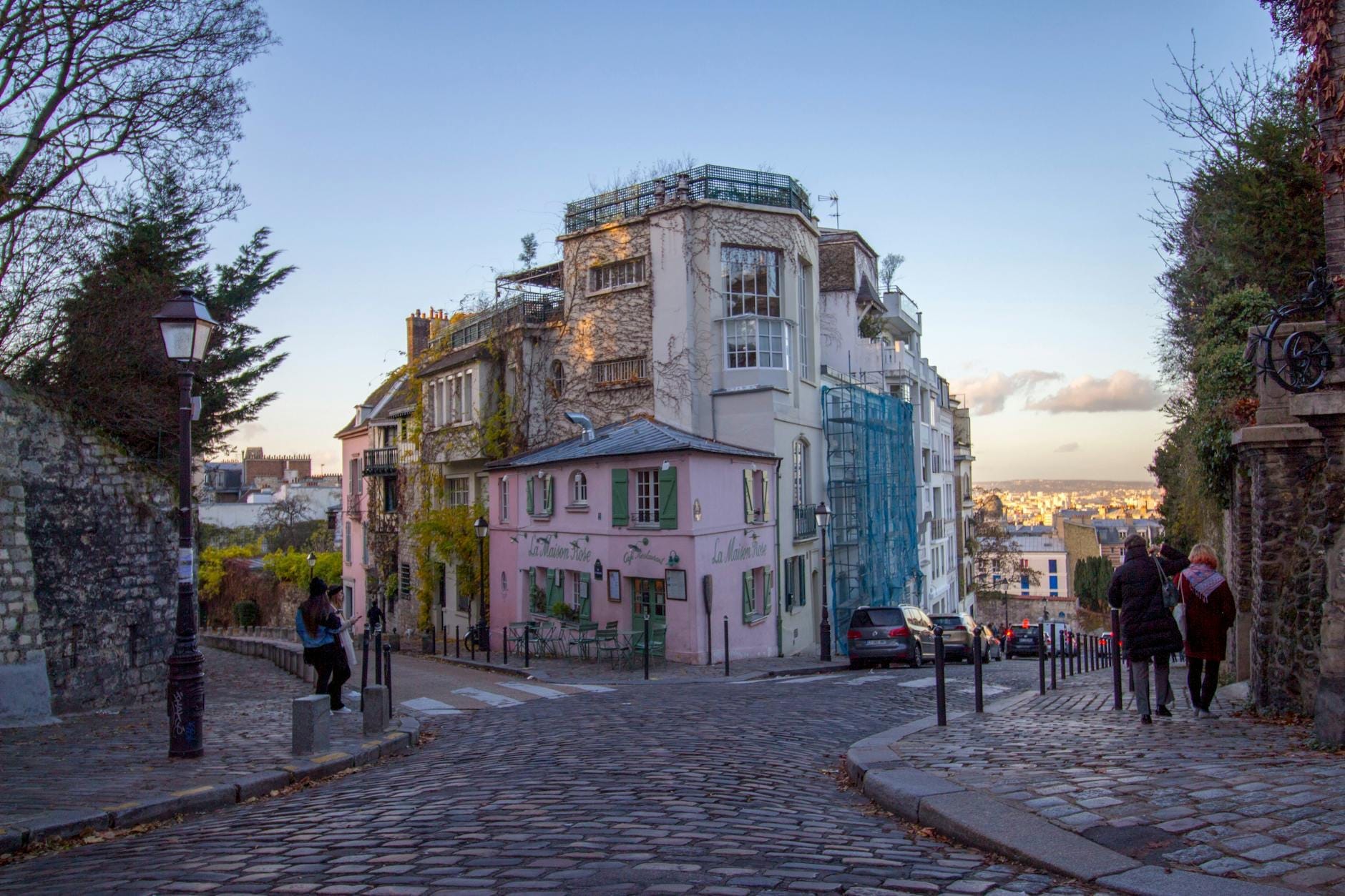 Una tranquilla strada acciottolata di Montmartre, fiancheggiata da edifici dal fascino antico al tramonto, che evoca l'atmosfera di un villaggio romantico parigino.