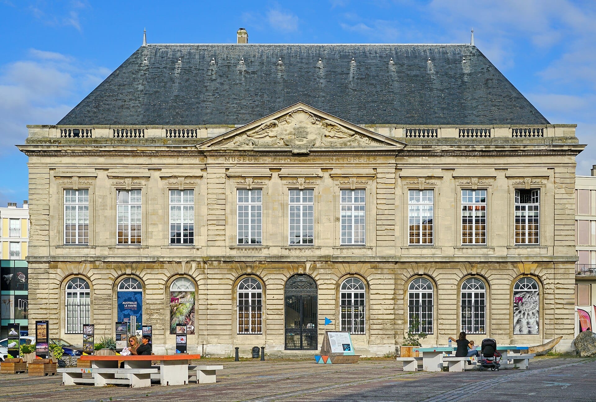 Il Muséum d'Histoire Naturelle du Havre presenta una maestosa facciata in pietra con grandi finestre e un frontone triangolare, sotto un cielo azzurro.