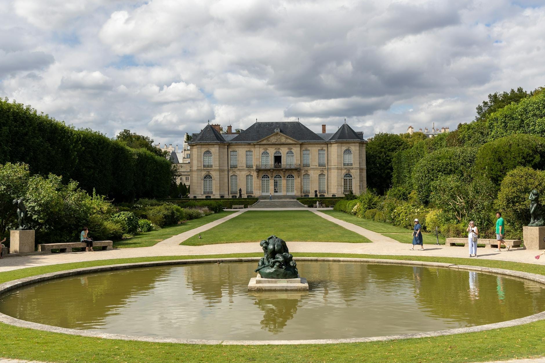 L'Hôtel Biron del Musée Rodin con i giardini formali, uno specchio d'acqua e Il Pensatore di Rodin al centro in primo piano sotto un cielo drammatico.