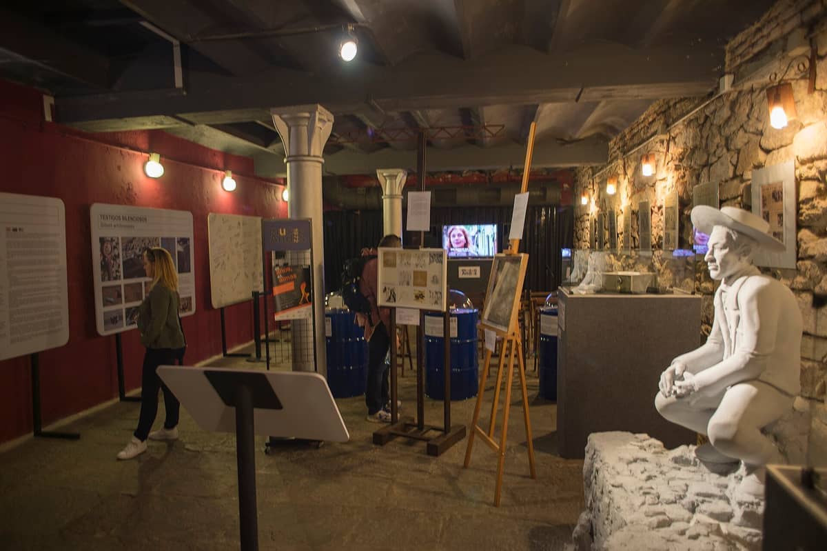 พื้นที่จัดแสดงนิทรรศการภายใน Museo Andes 1972 ซึ่งมีกำแพงหิน สิ่งประดิษฐ์ทางประวัติศาสตร์ แผงข้อมูล และรูปปั้นสีขาวของชายในเครื่องแบบ