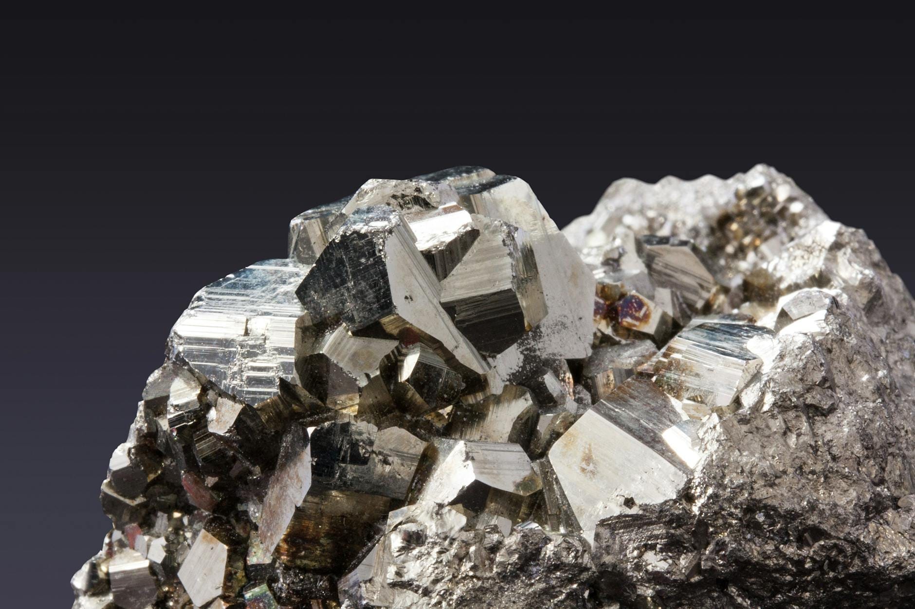 Nahaufnahme eines metallischen Mineralexemplars mit glänzenden, kantigen Kristallen, ausgestellt im Museo dell'Arte Mineraria in Iglesias.