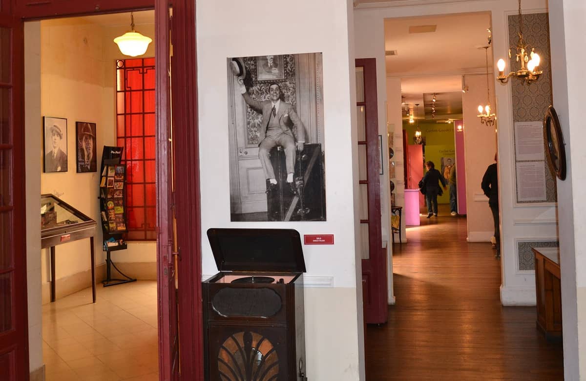 ภายในพิพิธภัณฑ์ Museo Casa Carlos Gardel ที่มีภาพถ่ายวินเทจ เครื่องเล่นแผ่นเสียง โคมไฟระย้า และนักท่องเที่ยวสำรวจห้องต่างๆ