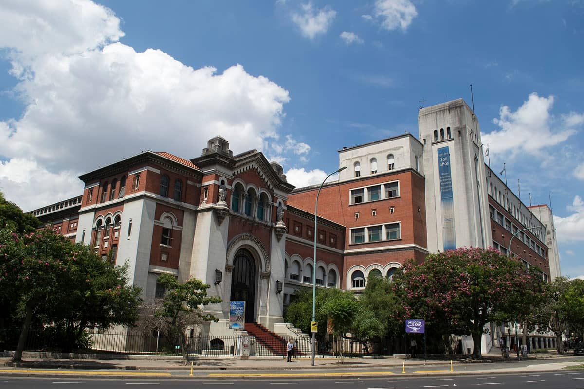 ภาพภายนอกของ Museo Argentino de Ciencias Naturales Bernardino Rivadavia ในบัวโนสไอเรส โดดเด่นด้วยอิฐแดงและหินสีขาวใต้ท้องฟ้าครึ้มเมฆ