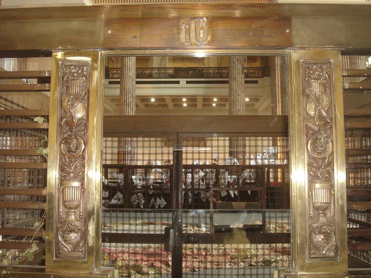 ทางเข้าของ Museo del Gaucho y de la Moneda ที่มีรายละเอียดทองเหลืองประดับประดา งานแกะสลักตกแต่ง และตะแกรงเหล็กในห้องโถงประวัติศาสตร์อันงดงาม