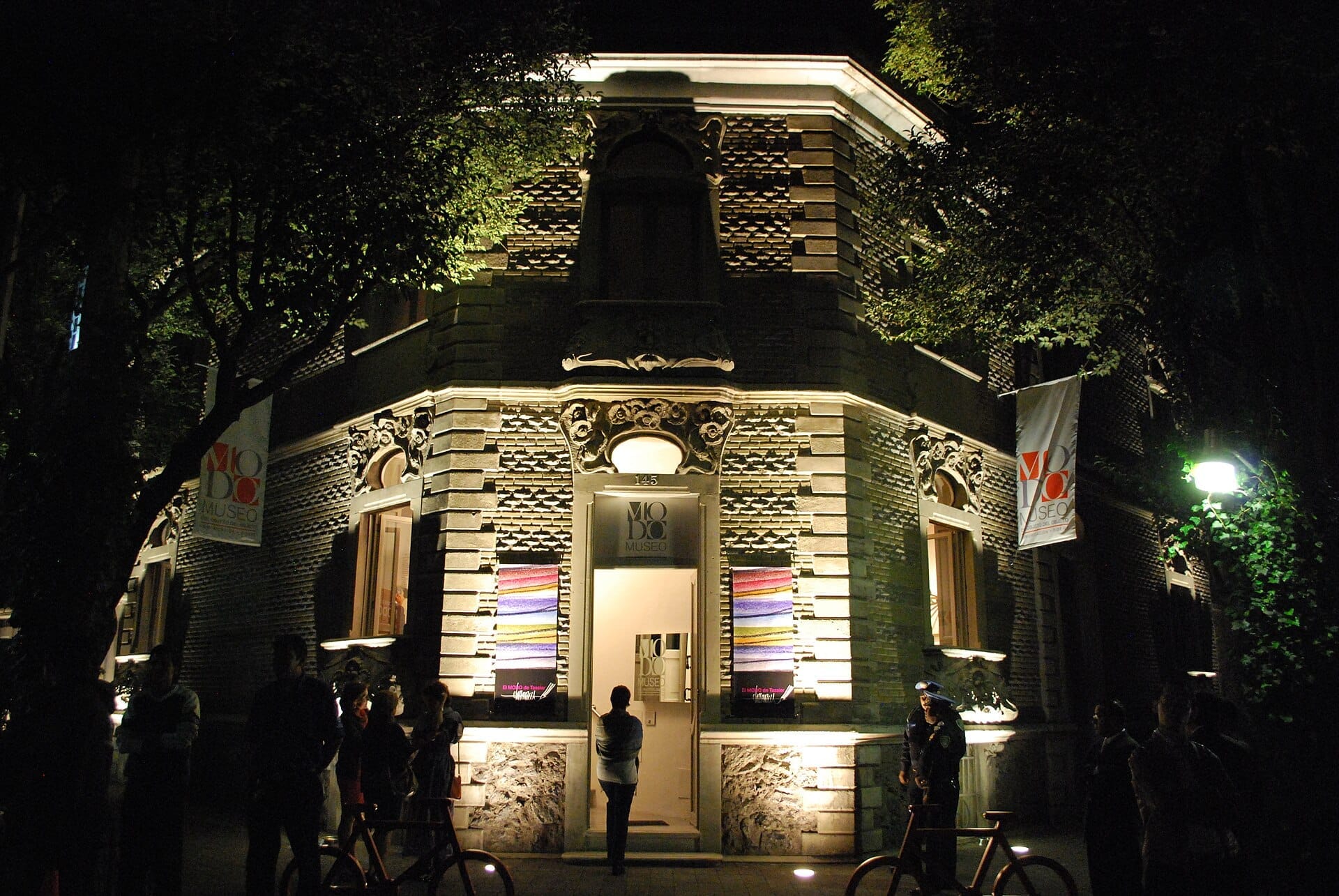 La facciata illuminata del Museo del Objeto del Objeto a Città del Messico, con dettagli Art Nouveau e persone riunite fuori di notte.