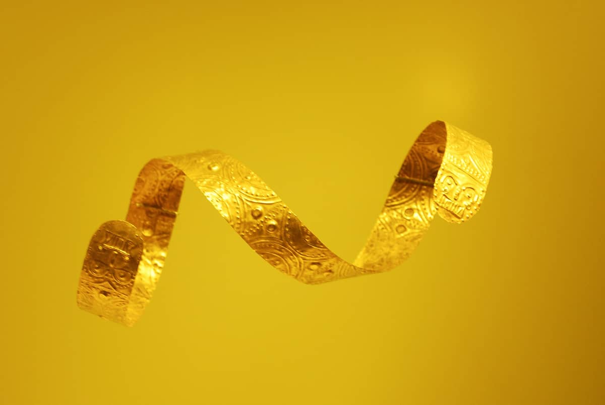 A pre-Hispanic gold artifact on display against a yellow background at Bogotá’s Museo del Oro, showing intricate indigenous metalwork representative of the museum’s collection.