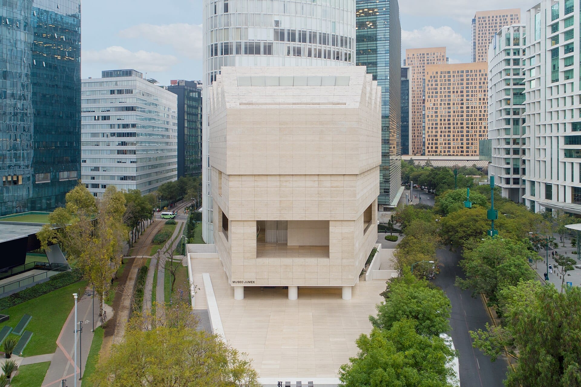 Vista frontale del Museo Jumex, un moderno edificio in pietra beige circondato da grattacieli di vetro e strade alberate a Polanco, Città del Messico.