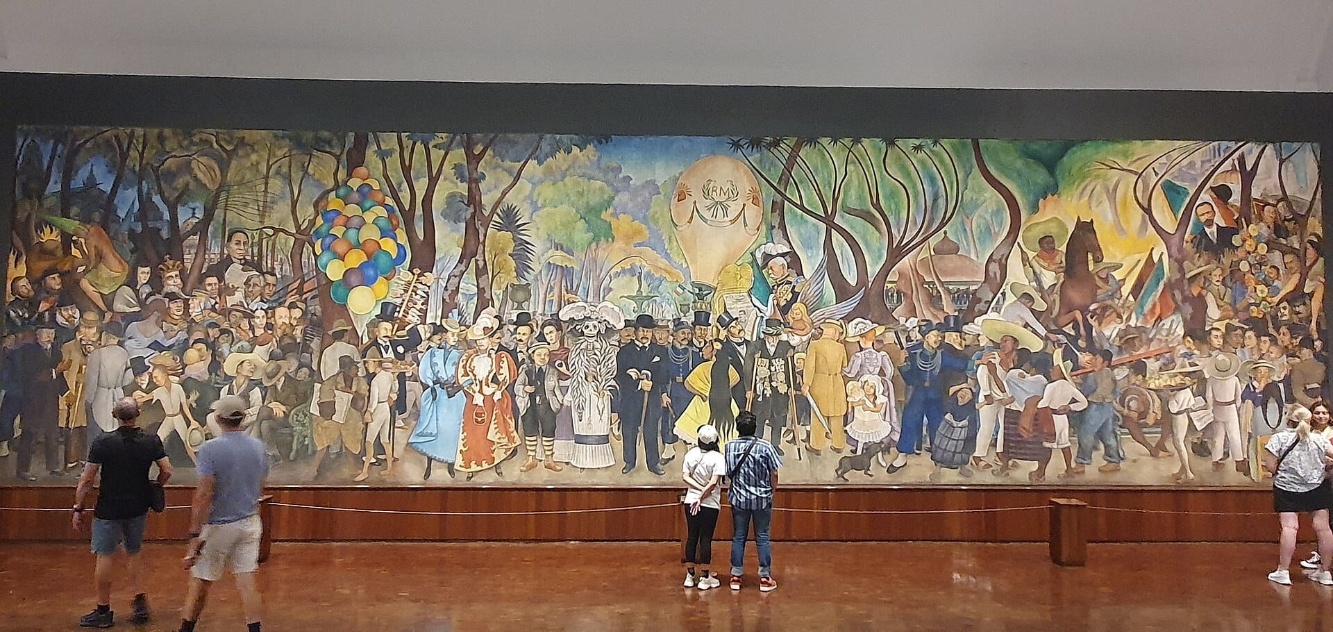 I visitatori si trovano davanti al vivace murale di Diego Rivera nel Museo Mural Diego Rivera, con figure storiche messicane in una grande scena colorata.