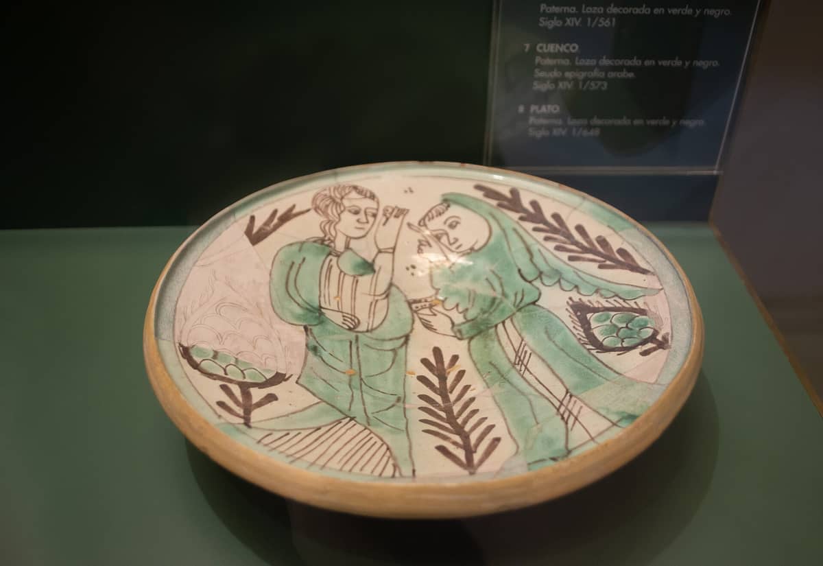 Esposizione di un piatto in ceramica medievale con figure dipinte in verde e marrone al Museo Nacional de Cerámica González Martí a Valencia, in Spagna.