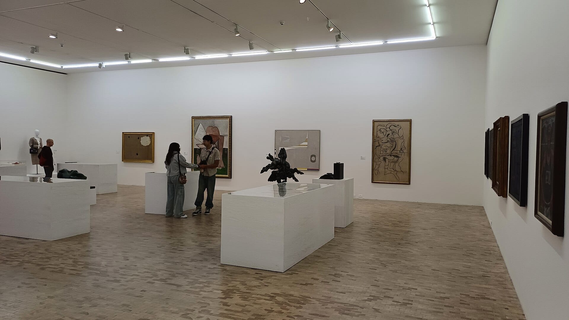 Vista interna del Museo Tamayo Arte Contemporáneo con opere d'arte moderne, pareti bianche, pavimento in legno e visitatori che ammirano le esposizioni.
