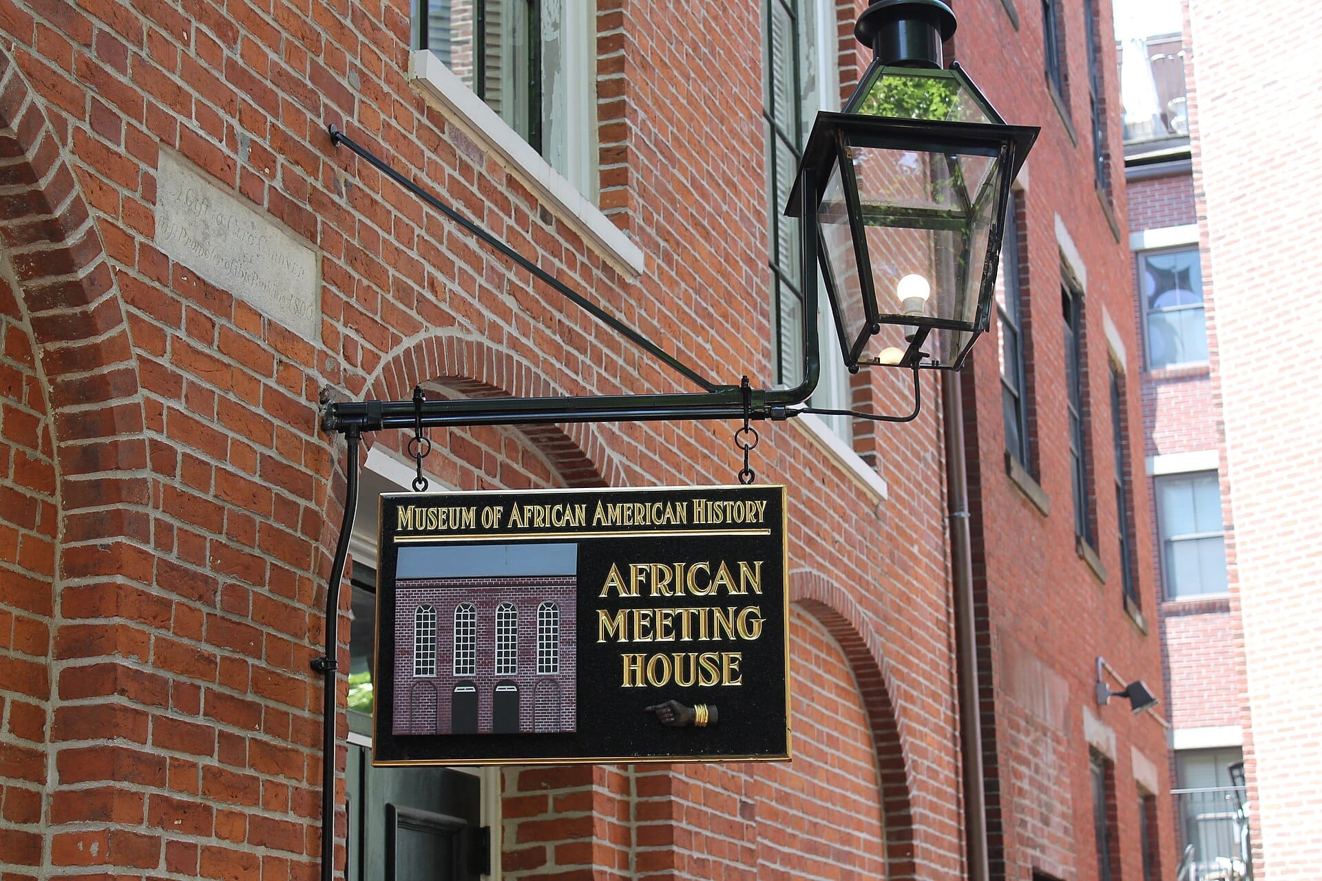 L'insegna dell'African Meeting House del Museum of African American History è appesa a un edificio in mattoni rossi sotto una lanterna nera vintage.