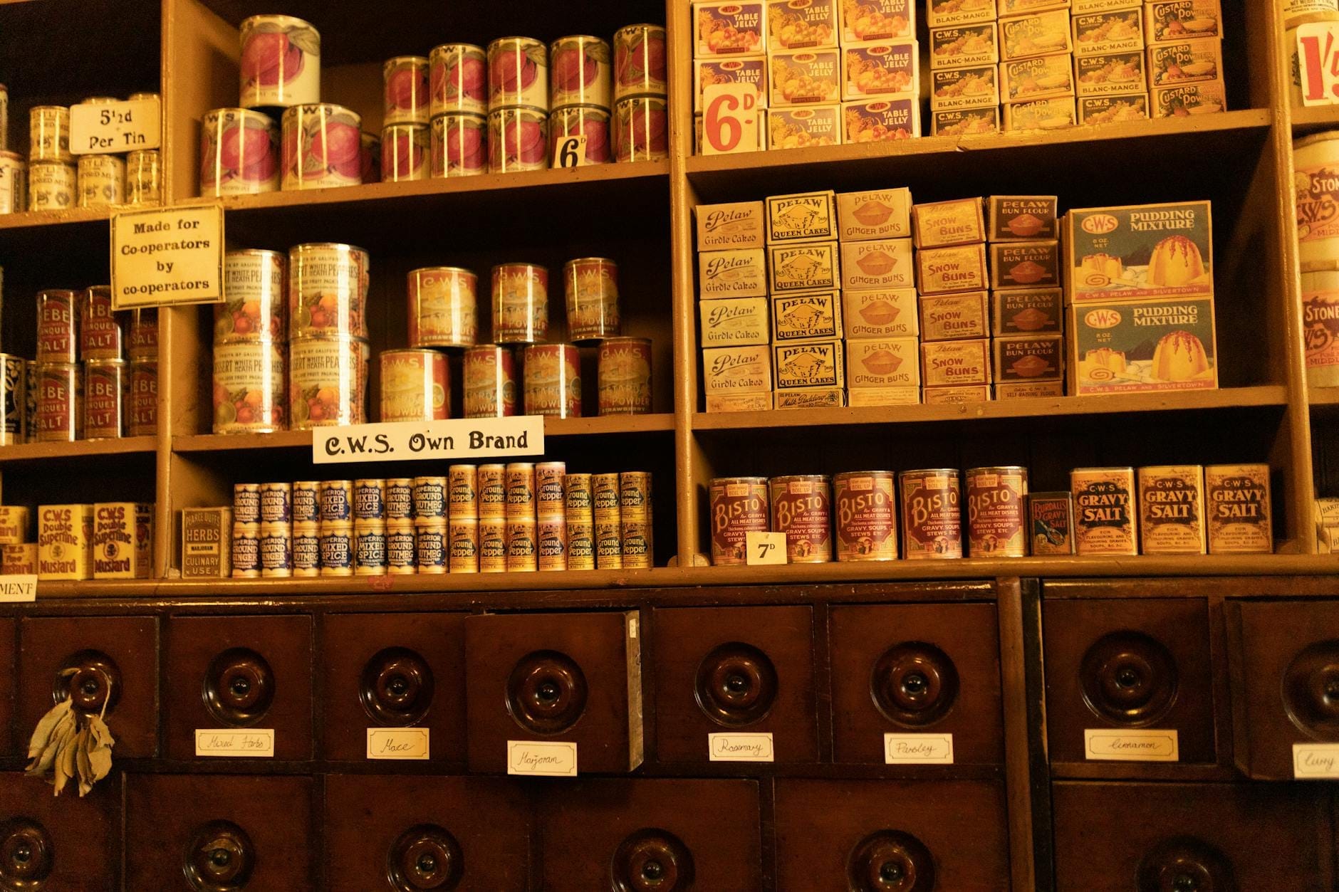 Scaffali pieni di scatole di latta, barattoli e confezioni vintage britanniche, disposte come in un negozio d'altri tempi, evocando decenni di storia del packaging.