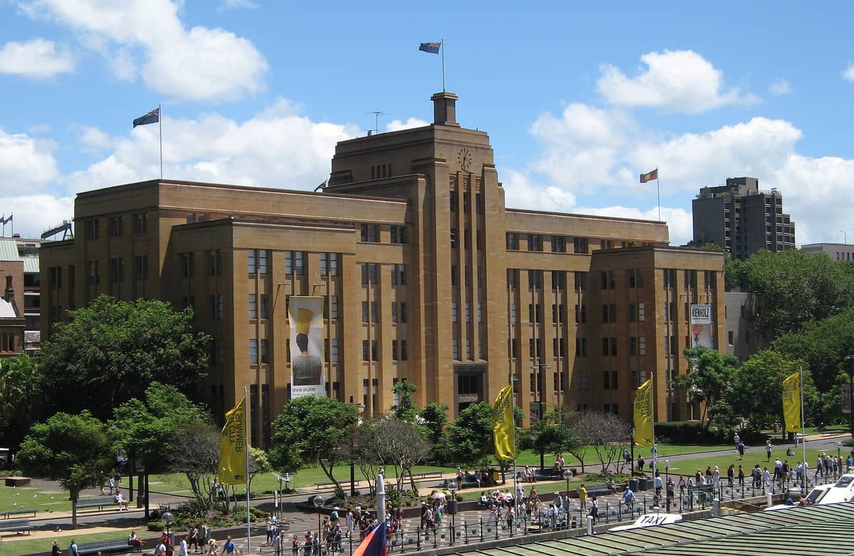 Widok na budynek Museum of Contemporary Art Australia – art deco, ludzie spacerujący w pobliżu, nabrzeże Sydney Harbour.