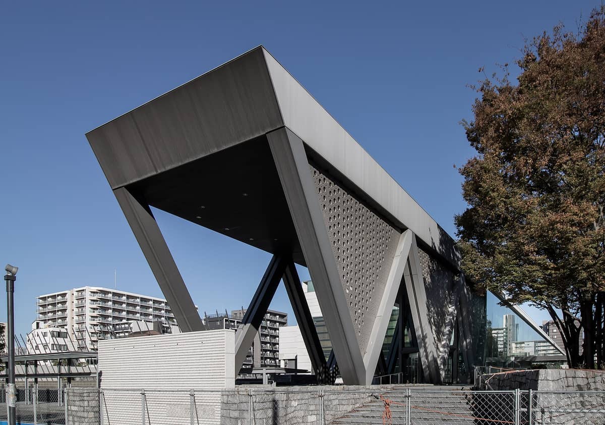 Exterior view of the Museum of Contemporary Art Tokyo (MOT) entrance, showcasing its modern triangular architectural design under a clear blue sky.