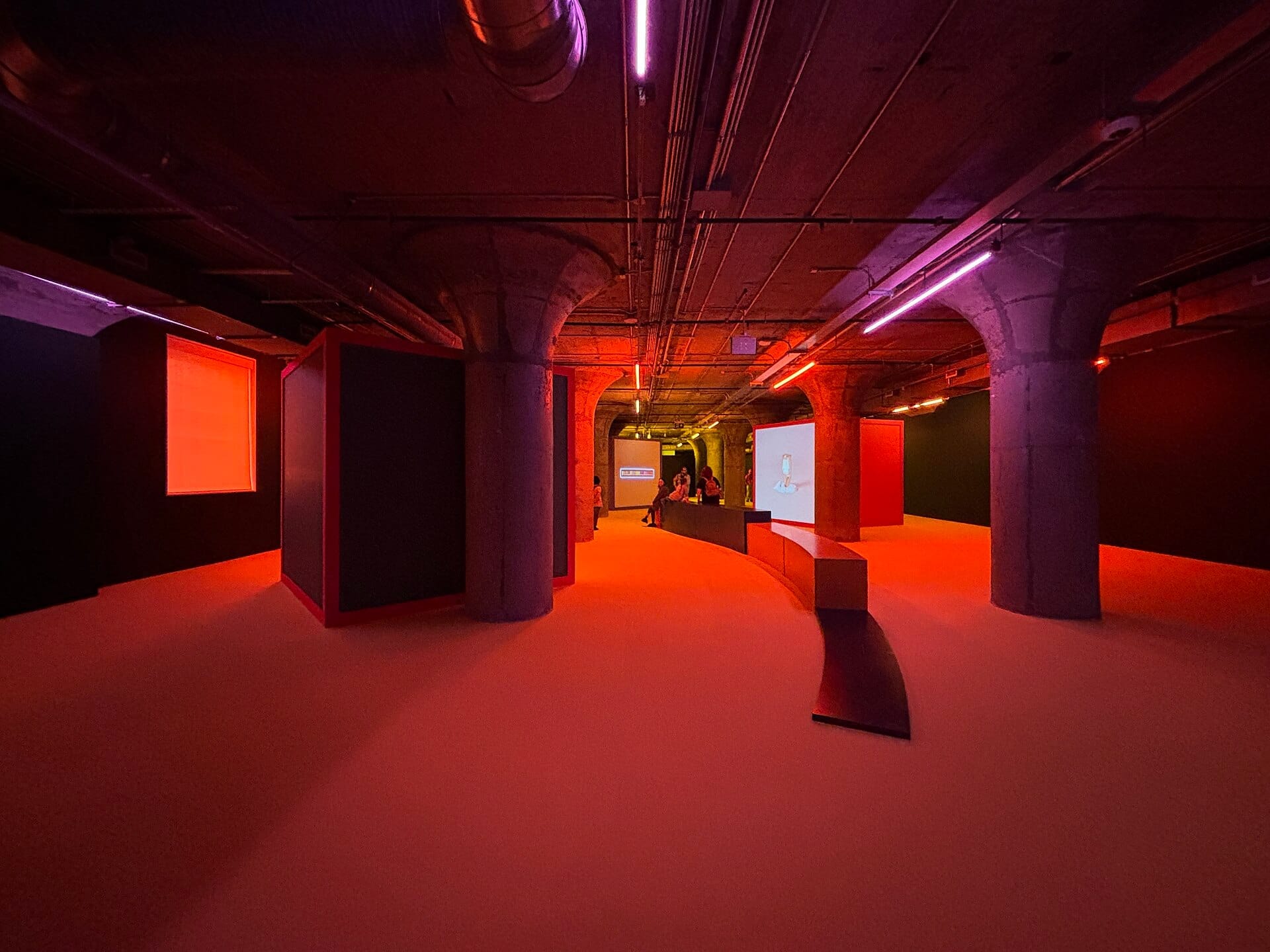 ภายในพื้นที่กว้างขวางของ Museum of Contemporary Art Toronto พร้อมเสาคอนกรีตโชว์ผิว นิทรรศการสมัยใหม่ และแสงสีส้มสดใส