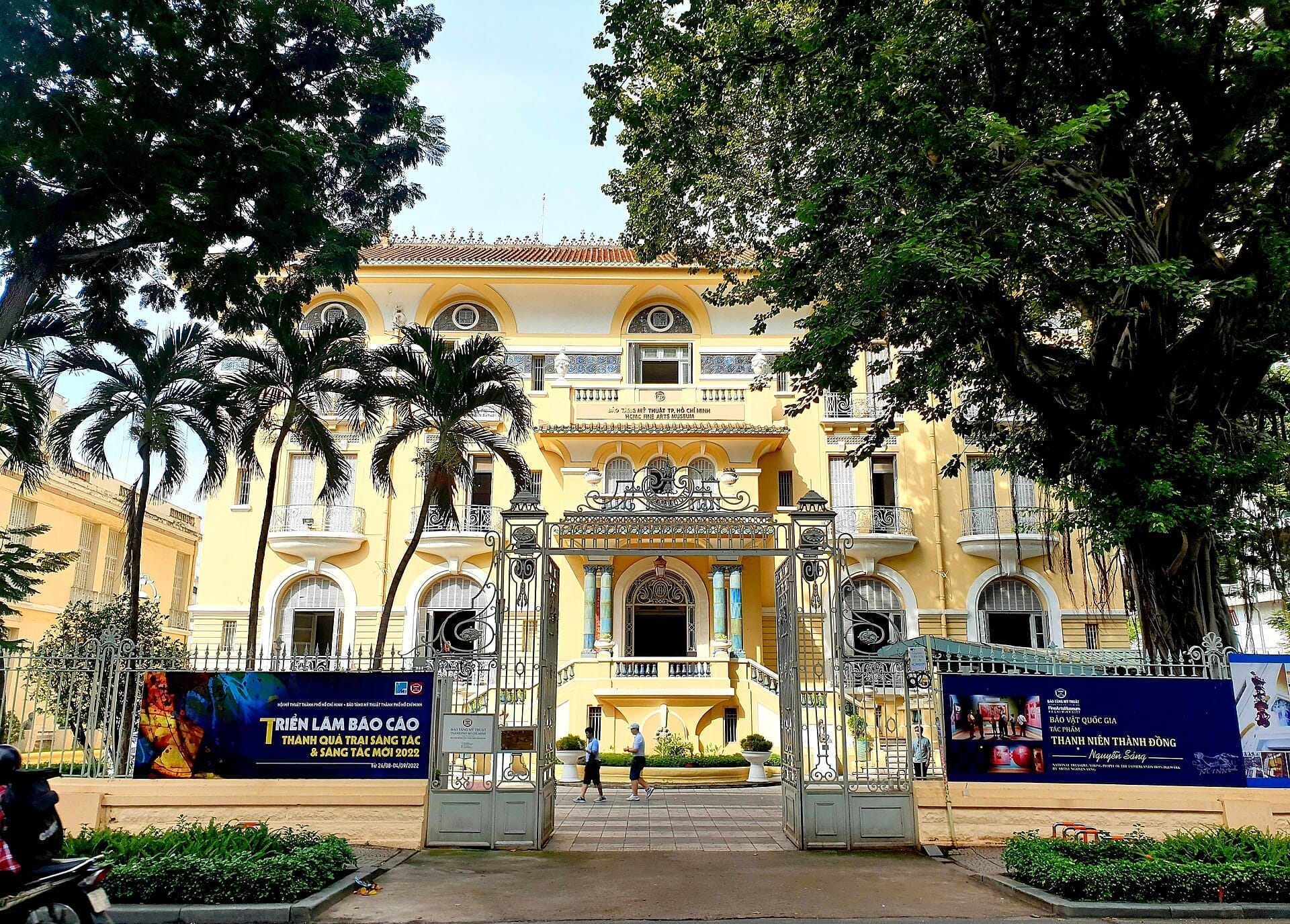 El Museo de Bellas Artes de Ho Chi Minh City con su fachada colonial francesa amarilla, elaboradas puertas de hierro y palmeras tropicales en la entrada.