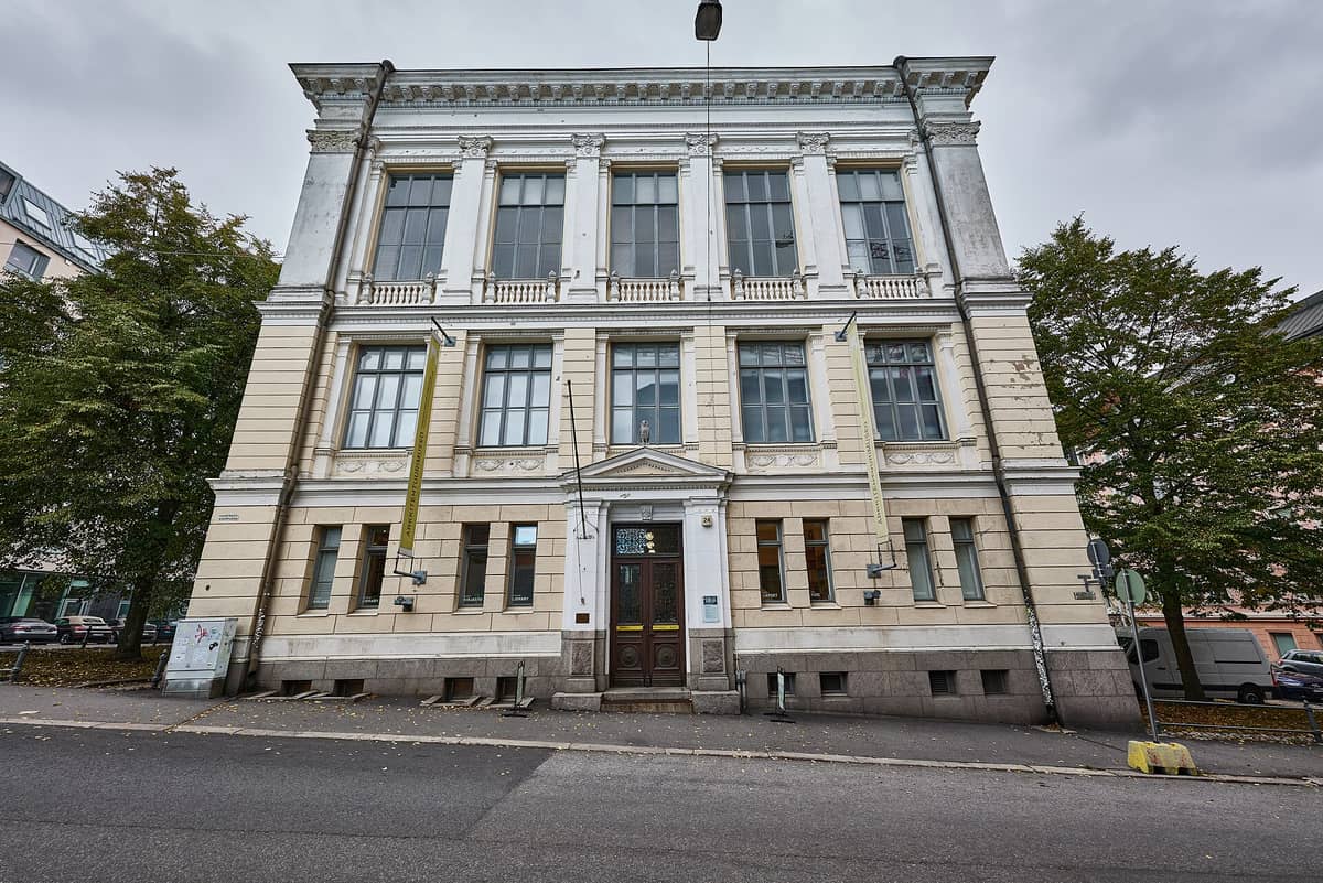 Fachada do Museu de Arquitetura Finlandesa em Helsinque, com seu design neoclássico, grandes janelas, detalhes ornamentados e entrada na Korkeavuorenkatu.